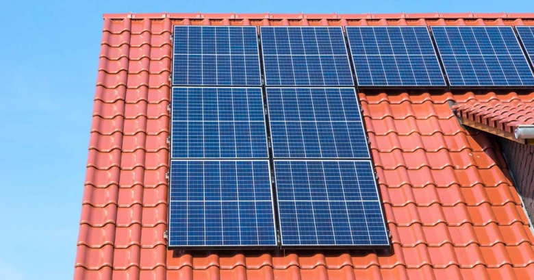Fotovoltaické panely na červené střechě domu.