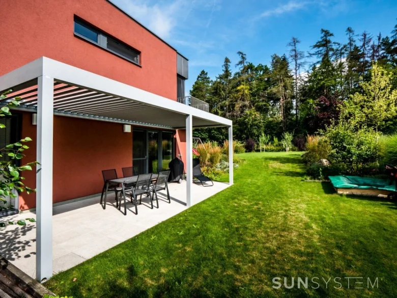 Bioklimatická pergola s venkovním nábytkem na terase u domu.