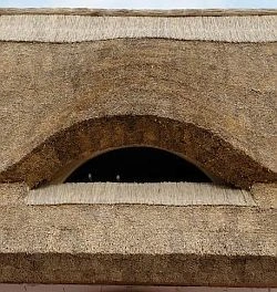 Detail doškové střechy s obloukovým otvorem.