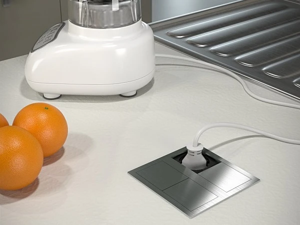 Vložená elektrická zásuvka v kuchyňské desce s připojeným spotřebičem.