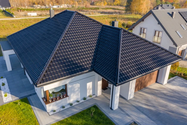 Moderní dům s tmavými střechovými taškami zblízka.