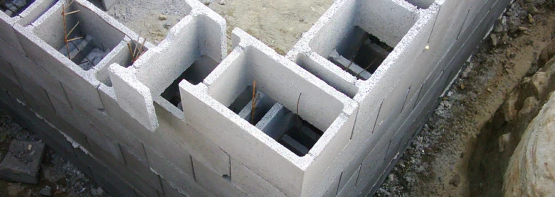 Část stavby z betonových bloků s výztuží v dutinách na staveništi.