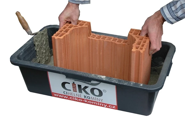 Ruční montáž cihlového komína v kontejneru s maltou