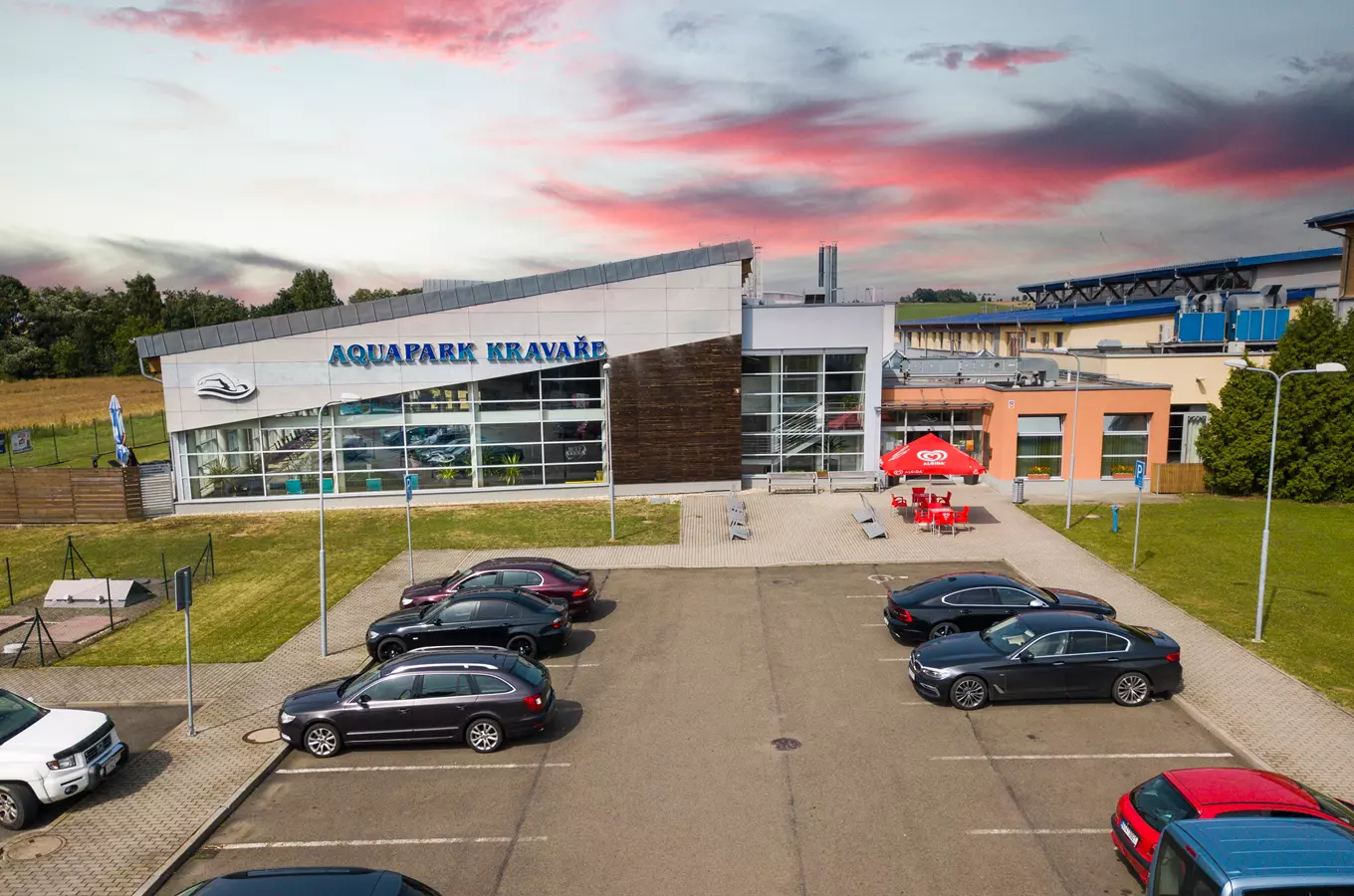 Vnější pohled na budovu Aquaparku v Kravařích s parkovištěm.