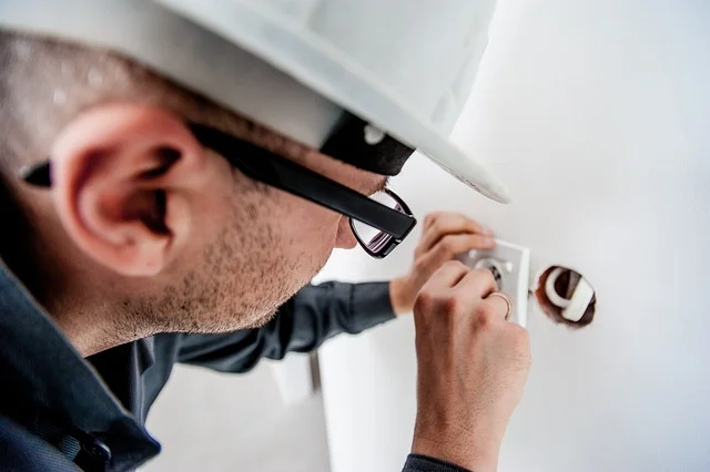 Elektrikář montuje zásuvku na stěnu v koupelně
