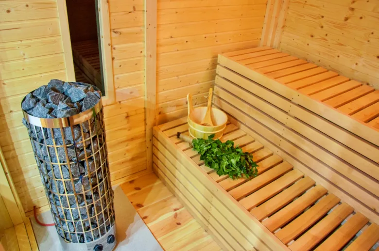 Ukončená finská sauna s kamenným topidlem a dřevěnými lavicemi.