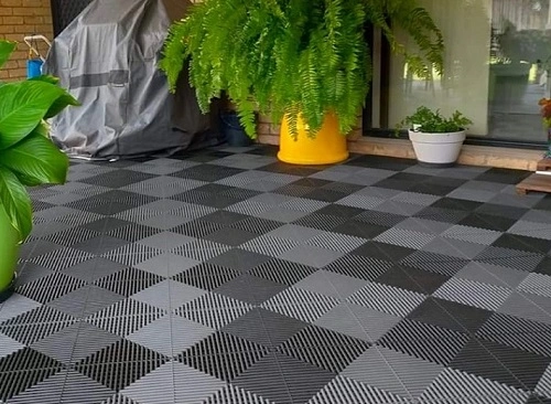 Sedlové dlaždice na balkóně s rostlinami v květináčích.