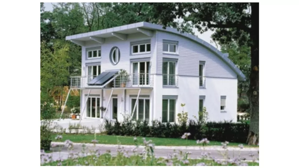 Moderní větraná fasáda domu s solárními panely a balkony.