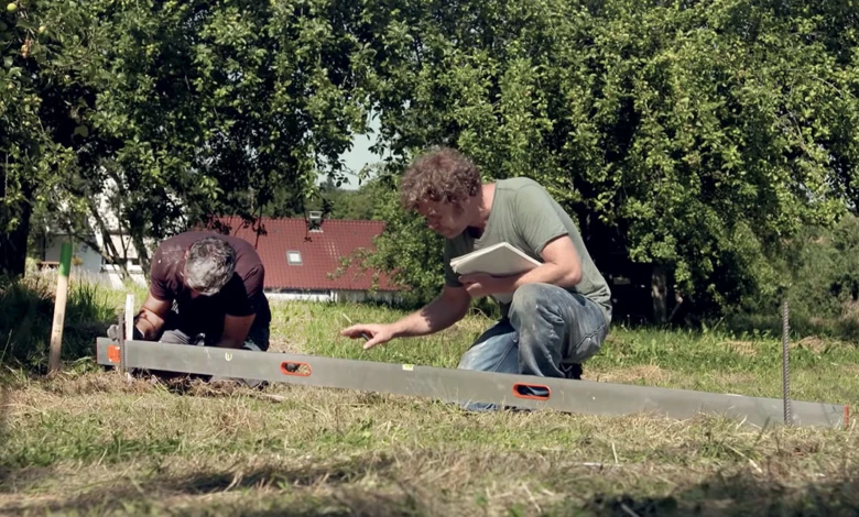 Dva muži připravují bednění základů pro betonování venku.