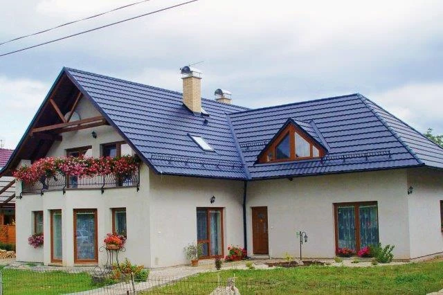 Moderní dům s plechovou střešní krytinou a štítovými okny.