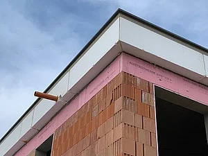 Detailní pohled na stavbu atiky střechy s izolací a cihlovou zdí.