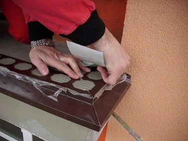 Ruční instalace tmavého dřevěného podlahového panelu na balkón.