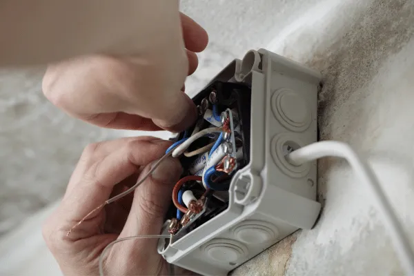 Ruční připojení vodičů v elektrickém rozvaděči pro domácí instalaci.