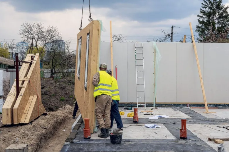 Montáž prefabrikované stěny pro trvalé bydlení na stavbě.