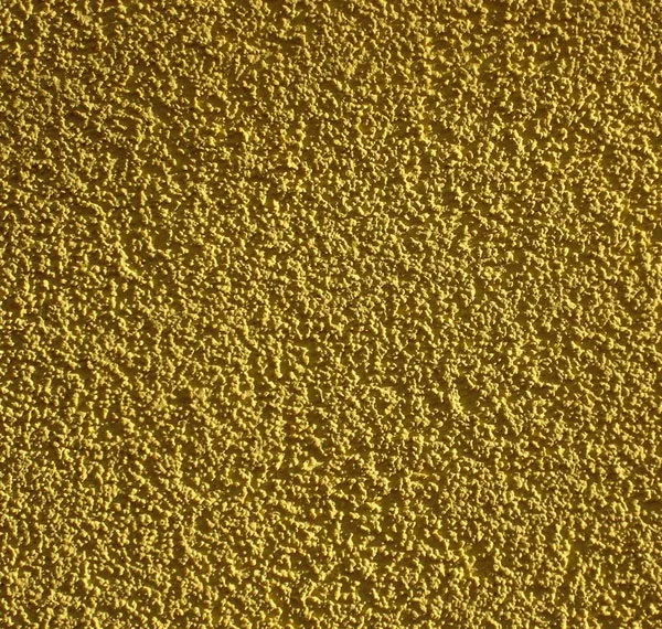 Detail texturované žluté fasádní omítky na zdi.