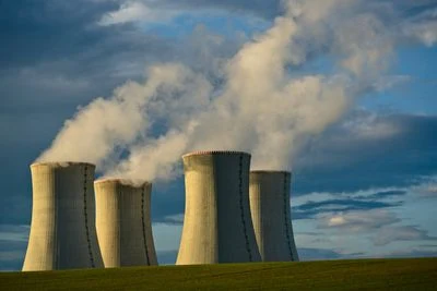 Čtyři chladiče elektrárny vypouštějící páru na pozadí oblohy.