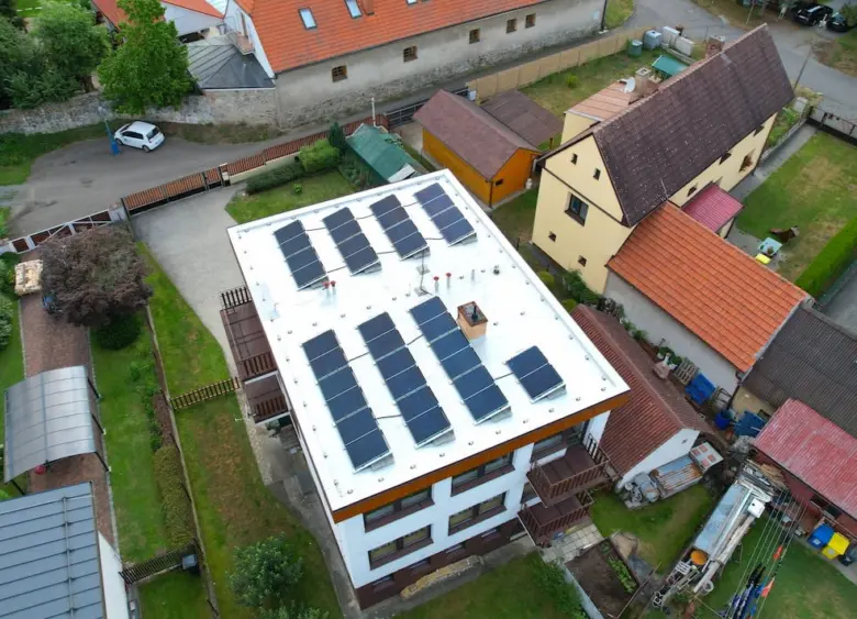 Vzdušný pohled na střechu domu s fotovoltaickými panely.
