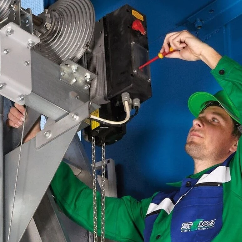 Technik opravuje průmyslová garážová brána šroubovákem.