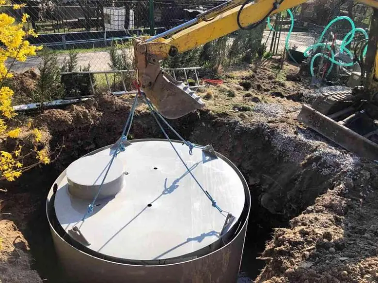 Montáž podzemní nádrže na dešťovou vodu pomocí výkopového stroje.