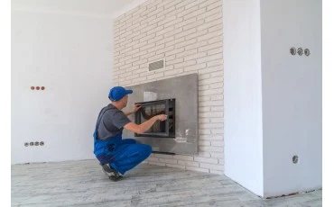 Muž instaluje komínový ventilátor do zdi během rekonstrukce.