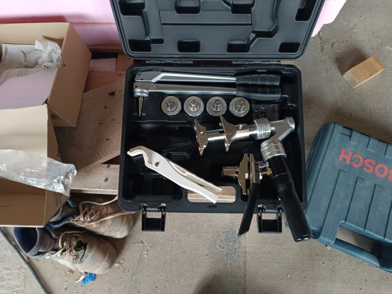 Nástroje pro instalaci plastových vodovodních trubek v otevřené krabici.