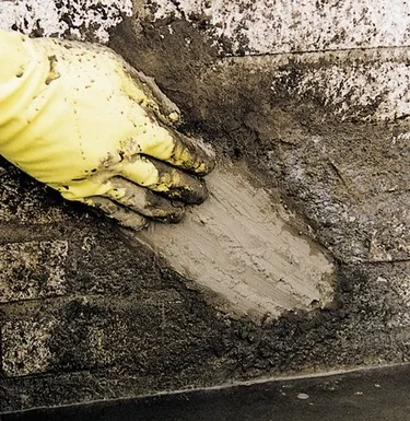 Ruční aplikace hydroizolačního stěrku na zdivo.
