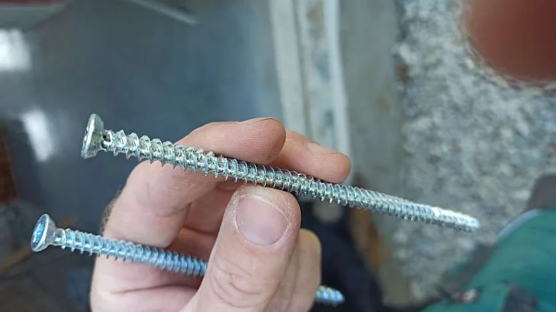 Ruce drží dva turbošrouby před zdí.