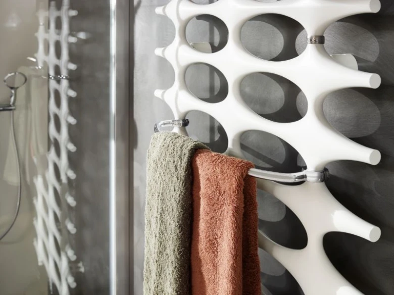 Modern bílý designový topný žebřík s utěrky v koupelně.