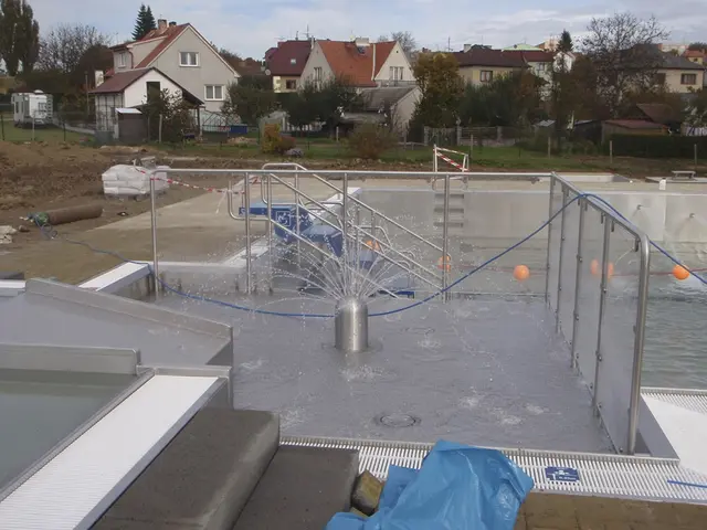 Nová venkovní plavecký bazén ve výstavbě s fontánou uprostřed.