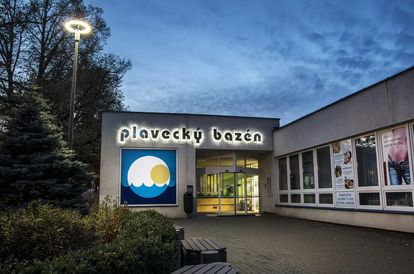 Vstup do plaveckého bazénu s osvětleným nápisem v západu slunce.