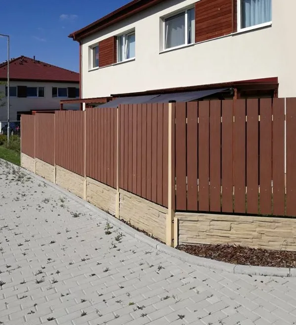 Hnědá dřevěná plot s kamenným základem u domu.