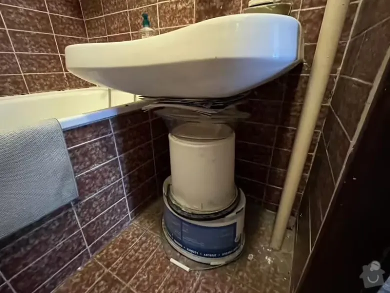 Bílá umyvadlo během opravy v koupelně s nádobami pod ním.