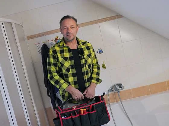 Muž s nářadím pro opravu sprchového přepínače a baterie