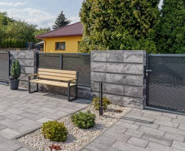 Dokončená dlažba na zahradě s lavičkou a plotem.