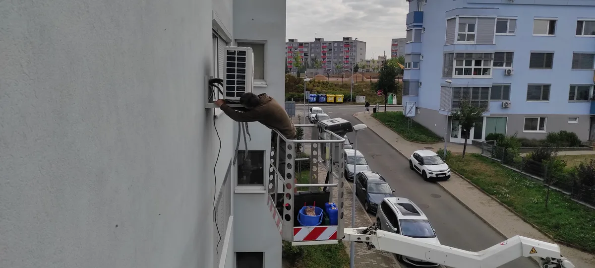 Technik čistí venkovní jednotku klimatizace na budově v Brně.