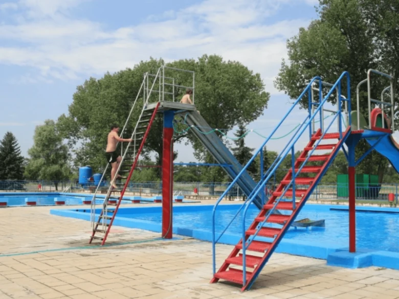 Venkovní bazén s vodními skluzavkami a schodišti pro koupání.