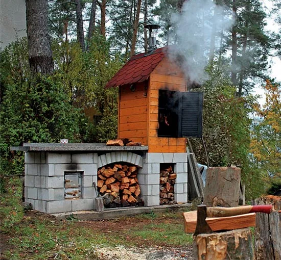 Zděná udírna s dřevem a dýmovnou komorou v lese
