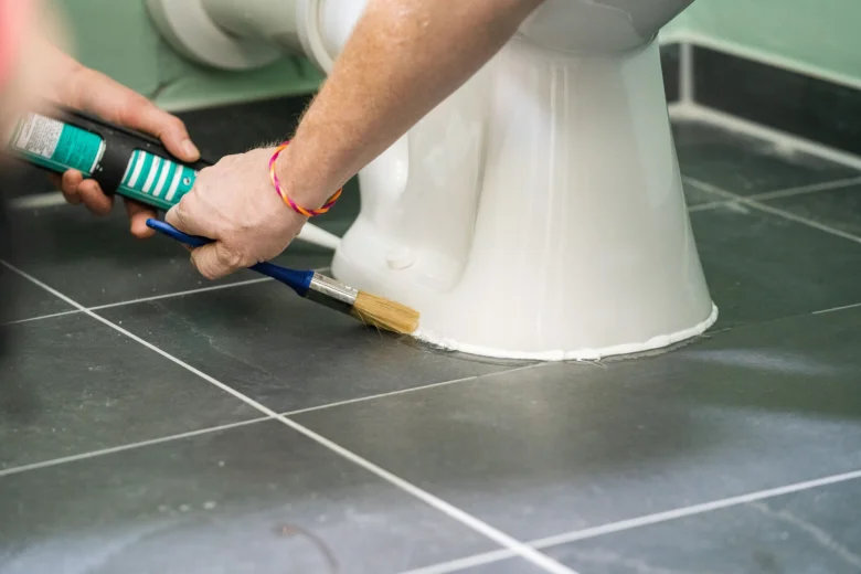 Náplast na instalaci záchodu: aplikace silikonu kolem základny.
