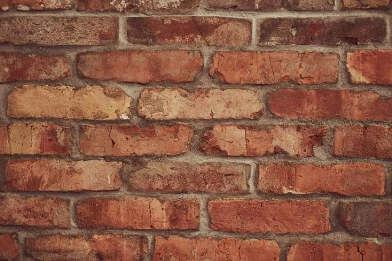 Zdivo z červených cihel s viditelnými spárami omítky.