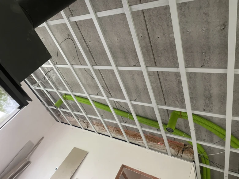 Zelené recirkulační potrubí v kovové konstrukci stropu.