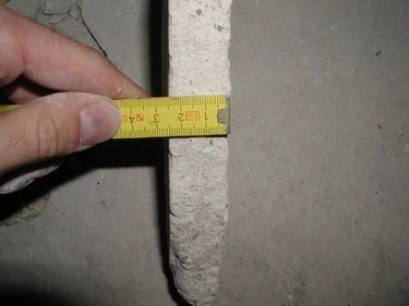 Měření tloušťky betonového potěru páskou na stavebním prvn.