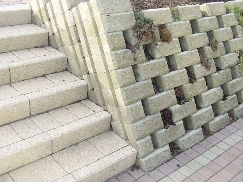 Schody z zámkové dlažby vedle opěrné zeď s rostlinami.