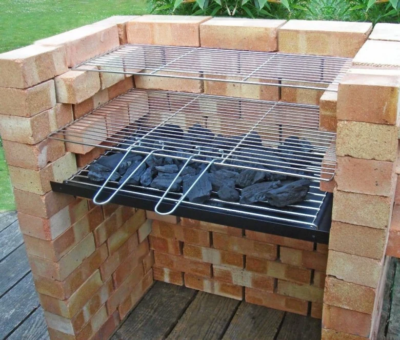 Zahradní gril z cihel s uhlím a mřížkami na vaření.
