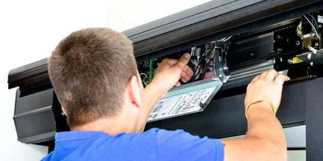 Muž opravuje automatizované brány pro garáž.