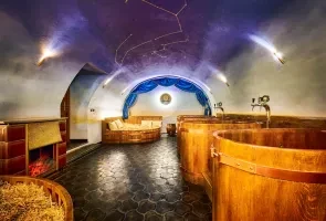 Vnitřní bazén s dřevěnými vanami pod hvězdnou stropní dekorací.