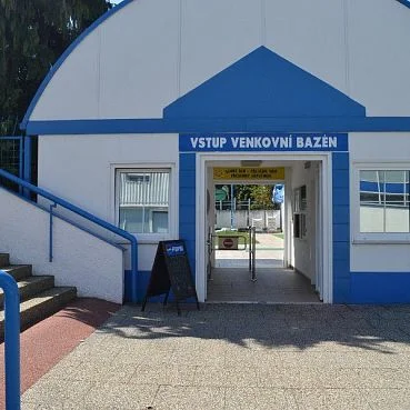 Budova vstupu do venkovního bazénu s modrým nápisem.