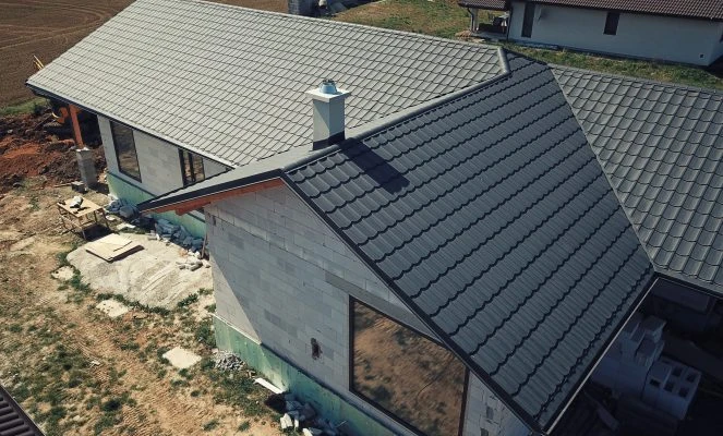 Stavba pultové střechy s viditelnou izolací na nehotovém domě.