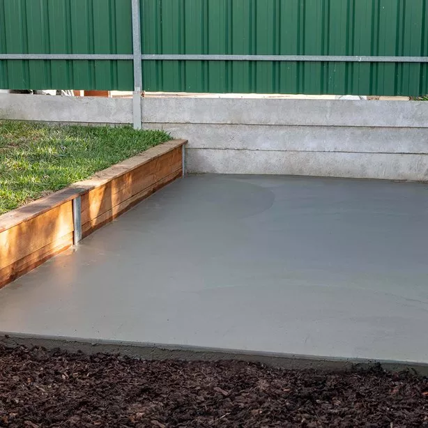 Čerstvě nalité betonové dlaždice vedle dřevěného okraje.
