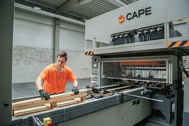Pracovník obsluhuje stroj na zpracování dřevěných palet v továrně.