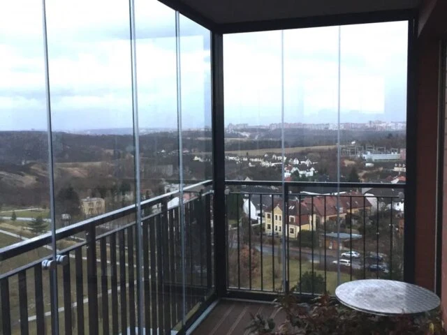 Zasklený balkon s výhledem na okolní krajinu.